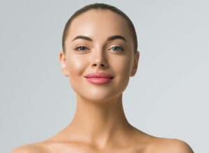Clean skin woman face close up skin beauty tanned face beautiful smile over blue background